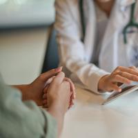 Image of a doctor showing a patient something on a tablet screen.