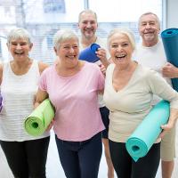 Group of happy seniors holding yoga mats