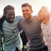 A group of diverse young men huddling together outside