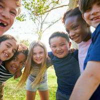 A group of smiling children huddled together outside