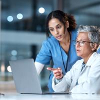 Image of two healthcare professionals in discussion in front of an open laptop