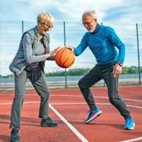 An older couple playing basketball outside.