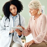 An older patient looking at a digital tablet with her doctor.