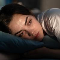 A woman lying in bed with insomnia.