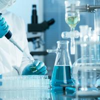 A photo of a blue gloved hand pipetting in a laboratory setting