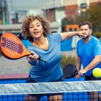 A woman and a man playing a racket sport outdoors.