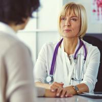 A doctor sitting at a desk talking to a patient.