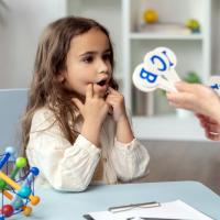 A young girl participating in a speech therapy session using flashcards.
