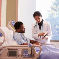 Hospital doctor with digital tablet talks to a male patient