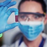 Scientist holds a vile of blood in gloved hand