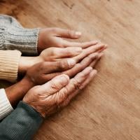 People across the age spectrum place their hands together.