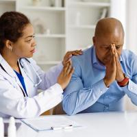 A female doctor comforting a worried male patient.