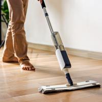 A person wet-mopping a hardwood floor in a home.