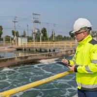 Environmental engineer takes notes at a wastewater treatment plant. 