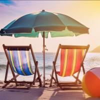 Two beach chairs under an umbrella overlooking the ocean.