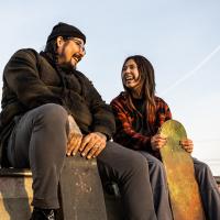 Two people sitting at the top of a ramp at a skate park