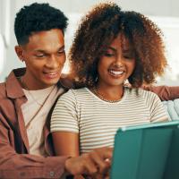 A young couple reading information on a tablet.