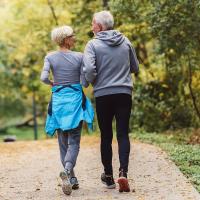 Cheerful active senior couple jogging in the park. Exercise together to stop aging. 