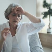 Middle-aged woman holds the back of her left hand to her forehead. 