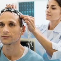 Doctor fixing electrodes on head of a patient 