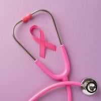 A pink awareness ribbon inside of a pink stethoscope on a pink background.