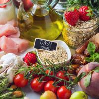 A variety of foods, including fresh fruits, vegetables, and other nutritious options, with a small black sign labeled "DASH diet" among the items.
